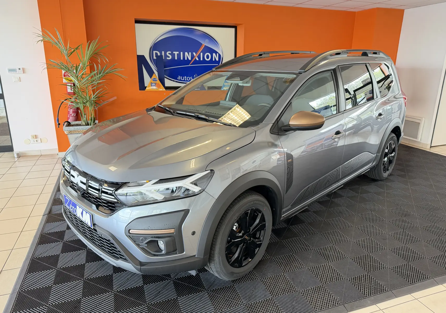 Vue 3/4 avant d'un Dacia Jogger gris schiste métallisé avec jantes noires et rétroviseurs bronze en showroom.