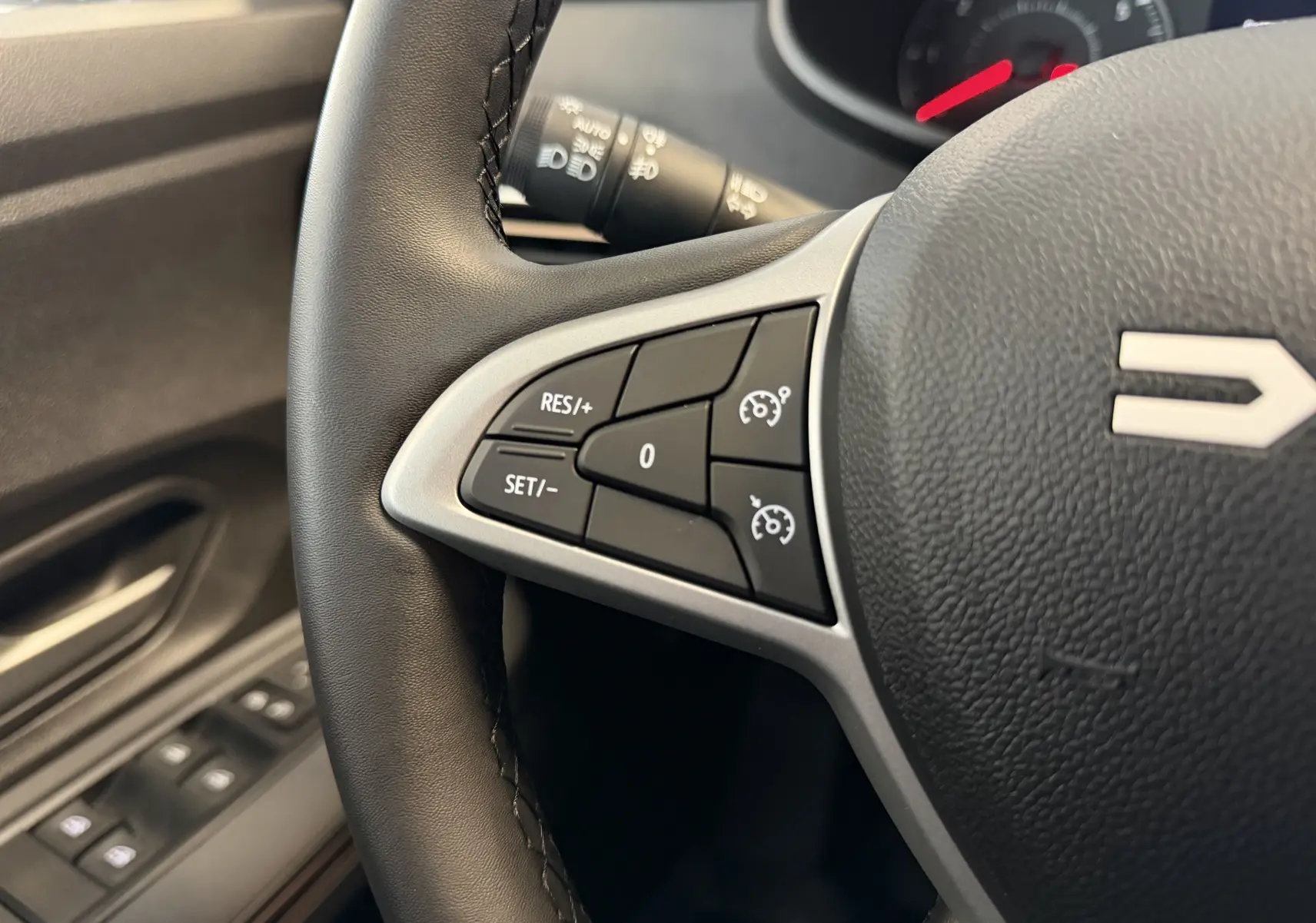 Gros plan sur le volant noir de la Dacia Jogger 2026, montrant les commandes de régulateur de vitesse côté gauche.