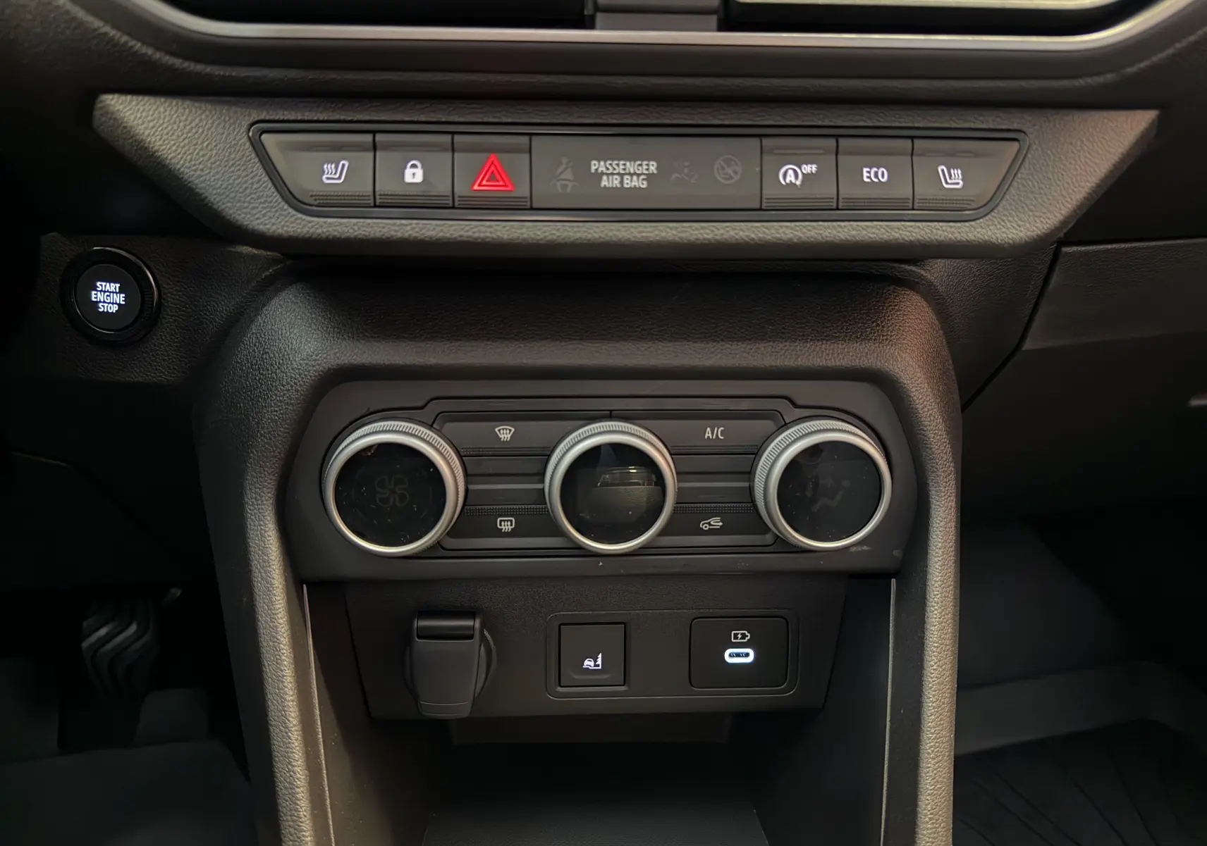 Vue rapprochée de la console centrale noire du Dacia Jogger 2026 avec commandes climatisation et bouton Start Engine Stop.