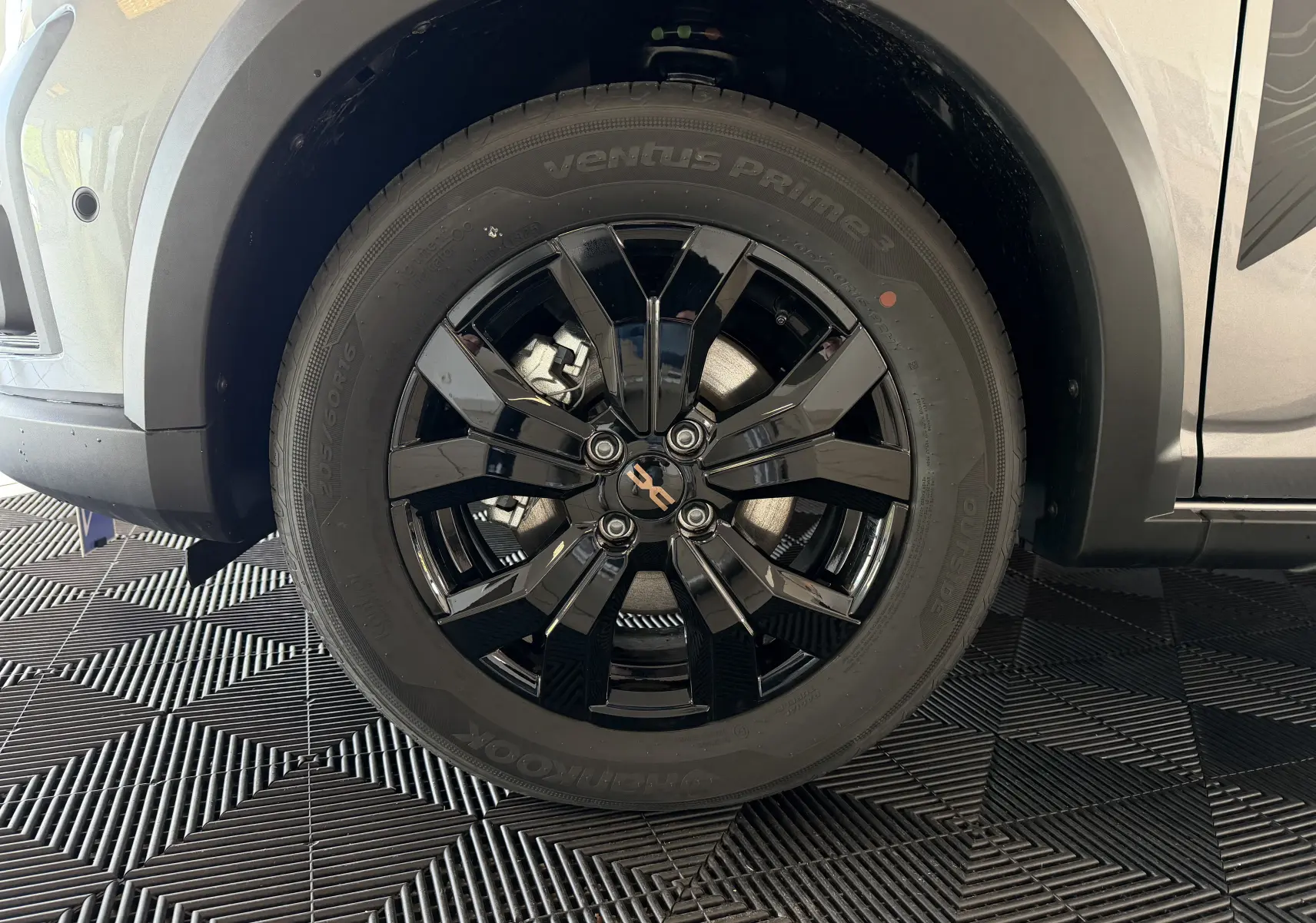 Gros plan sur la roue avant droite d’un Dacia Jogger gris schiste métal avec jante noire brillante à 5 doubles branches.