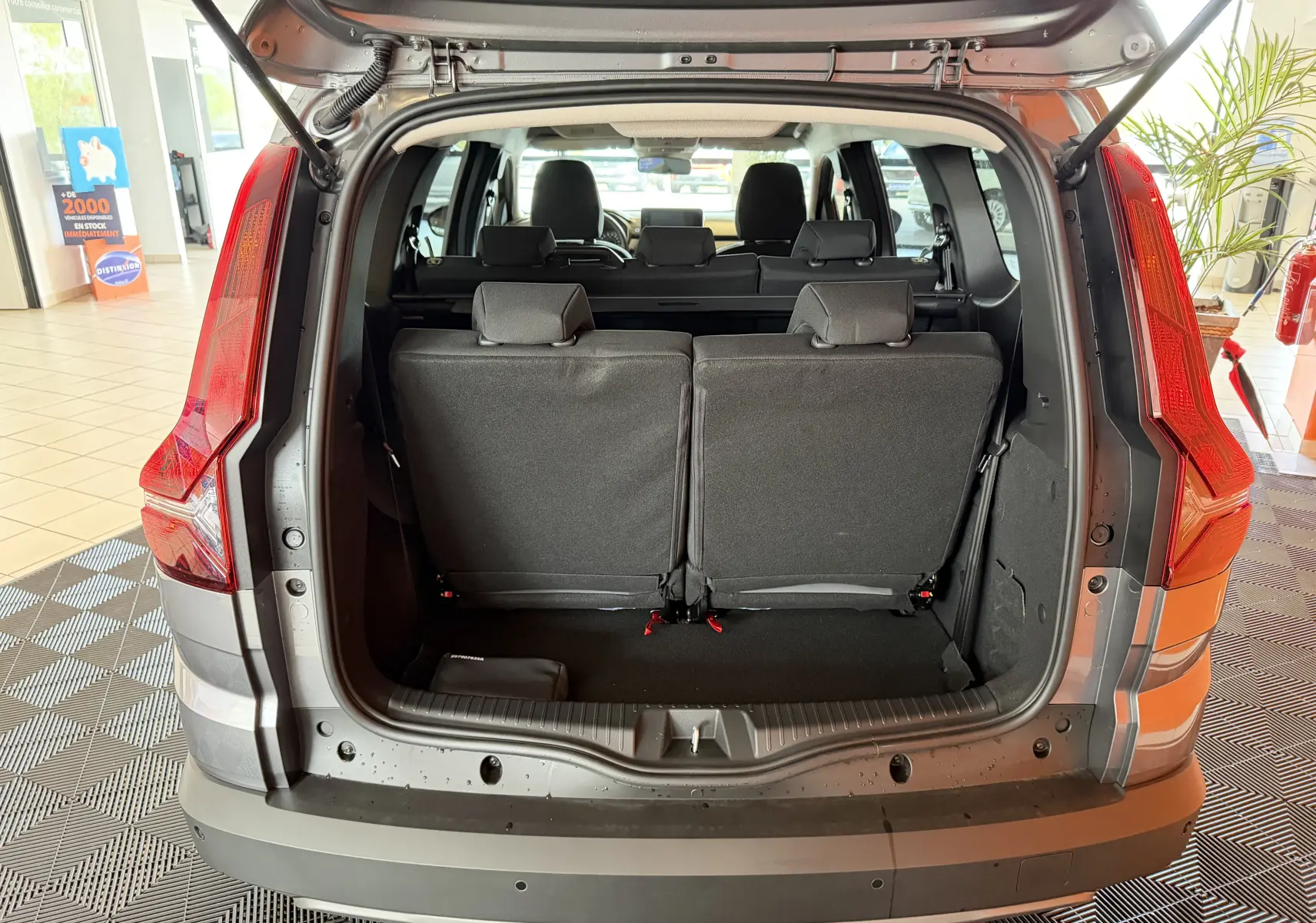 Vue arrière du coffre ouvert du Dacia Jogger gris schiste métal, montrant les sièges rabattus et l'intérieur spacieux.