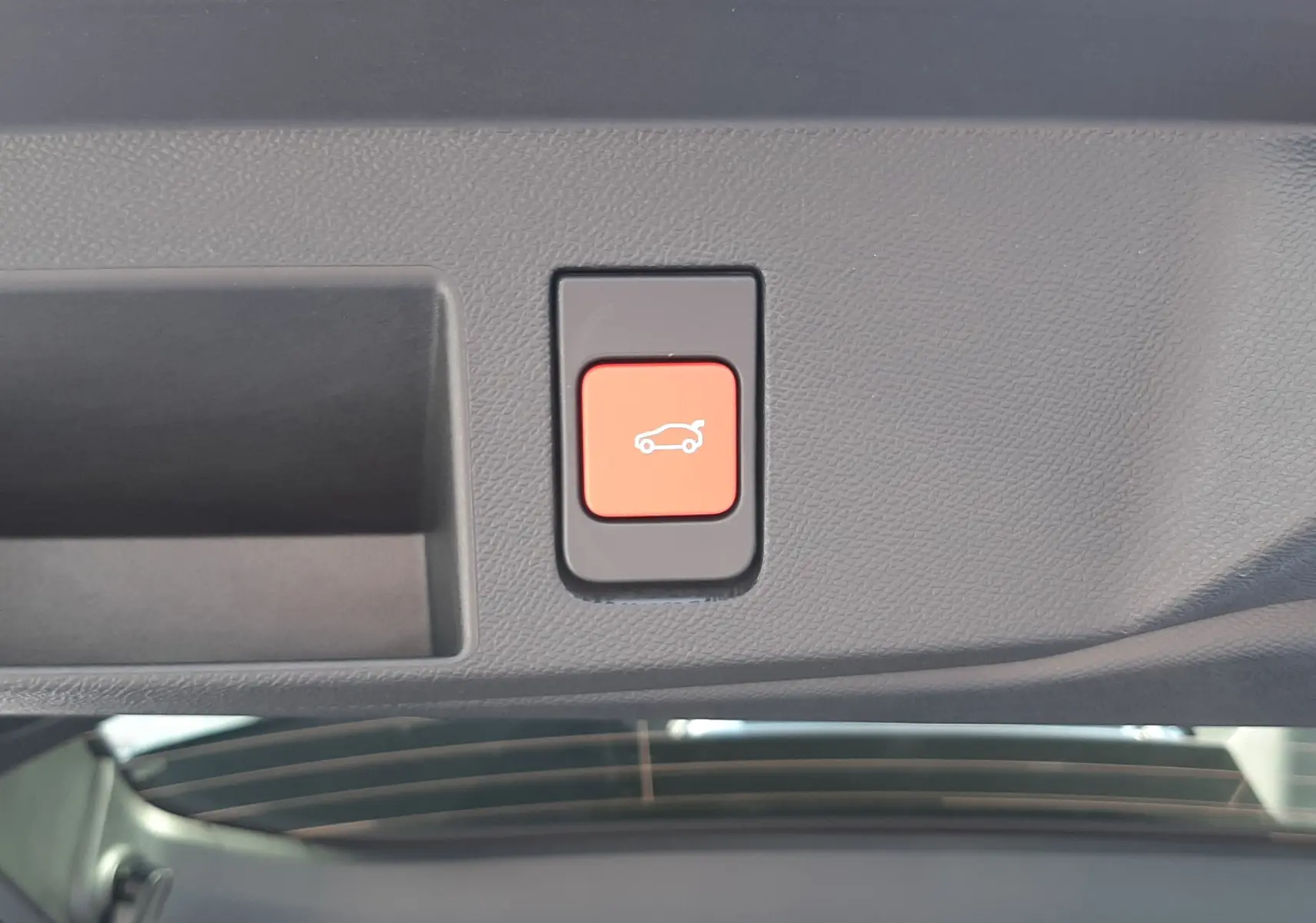 Bouton rouge de hayon électrique vu en gros plan à l'intérieur du coffre du Citroën C5 Aircross vert Astoria.