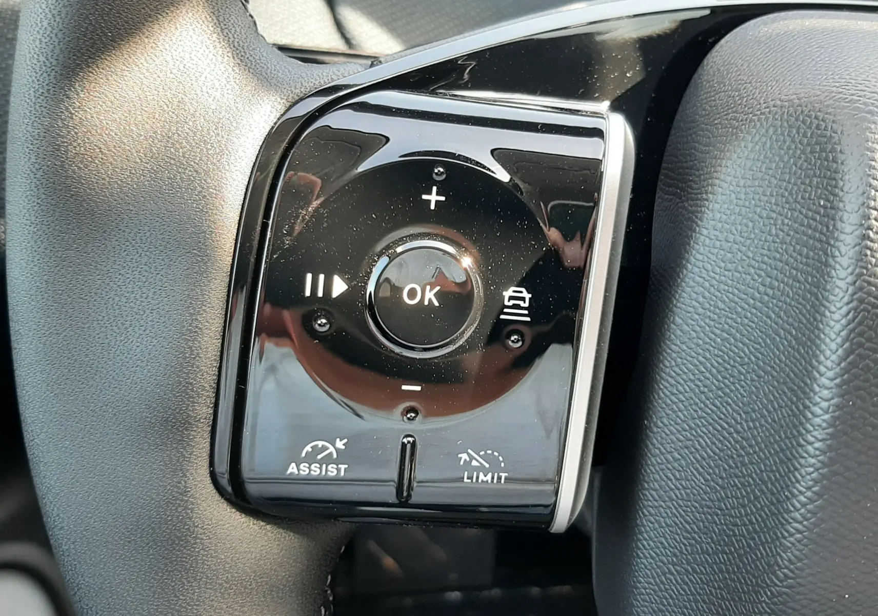 Gros plan sur les commandes noires du volant du Citroën C5 Aircross hybride 2026, avec boutons multifonctions et finition brillante.