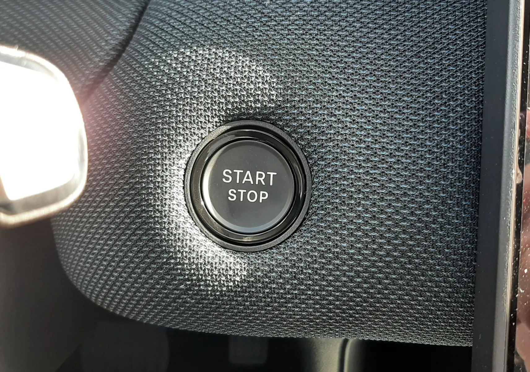 Bouton start-stop en gros plan sur tableau de bord texturé gris foncé du Citroën C5 Aircross hybride 2026.