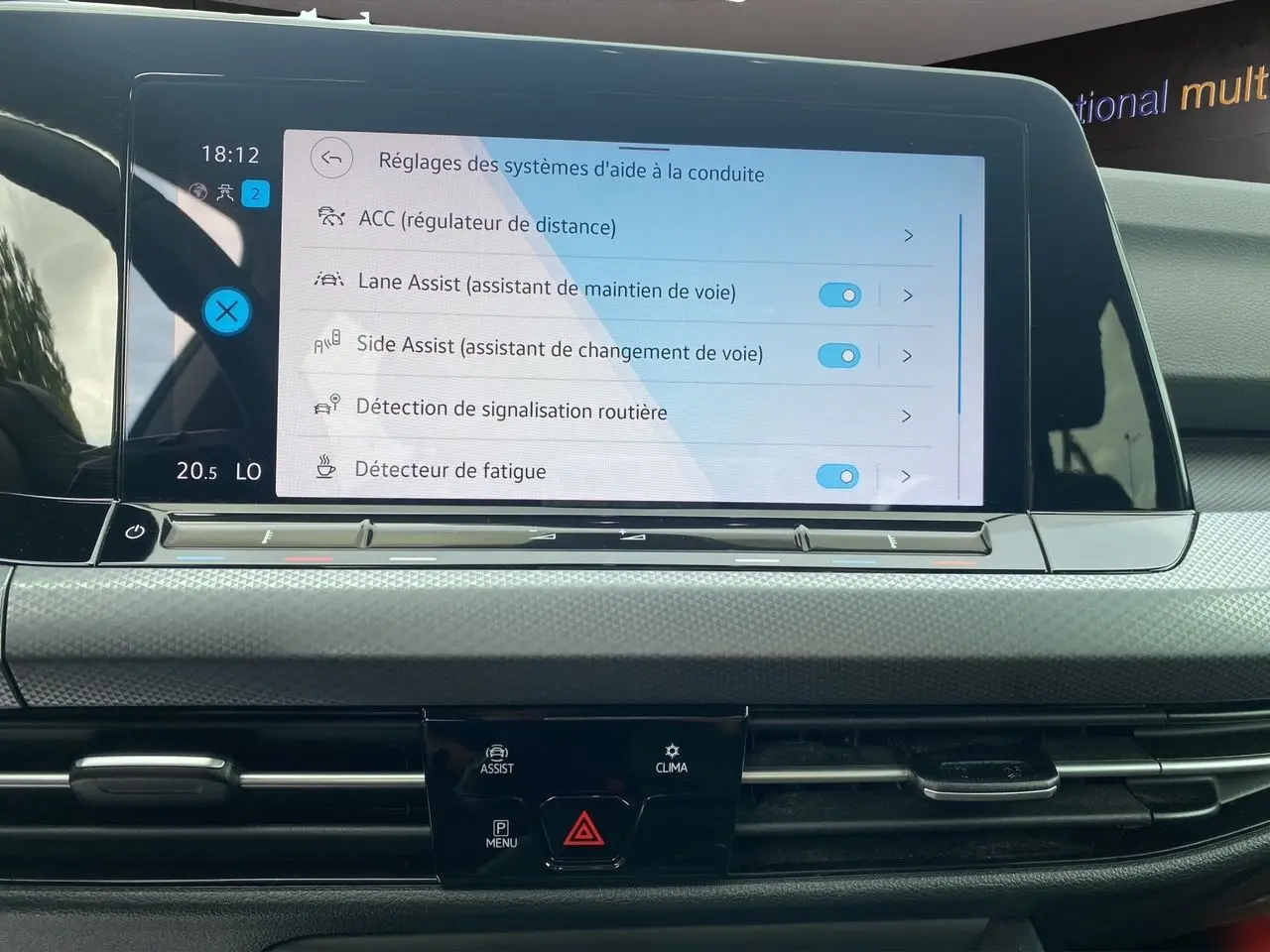 Écran tactile central de la Volkswagen Golf VIII noire de 2022 montrant les réglages d'aides à la conduite.
