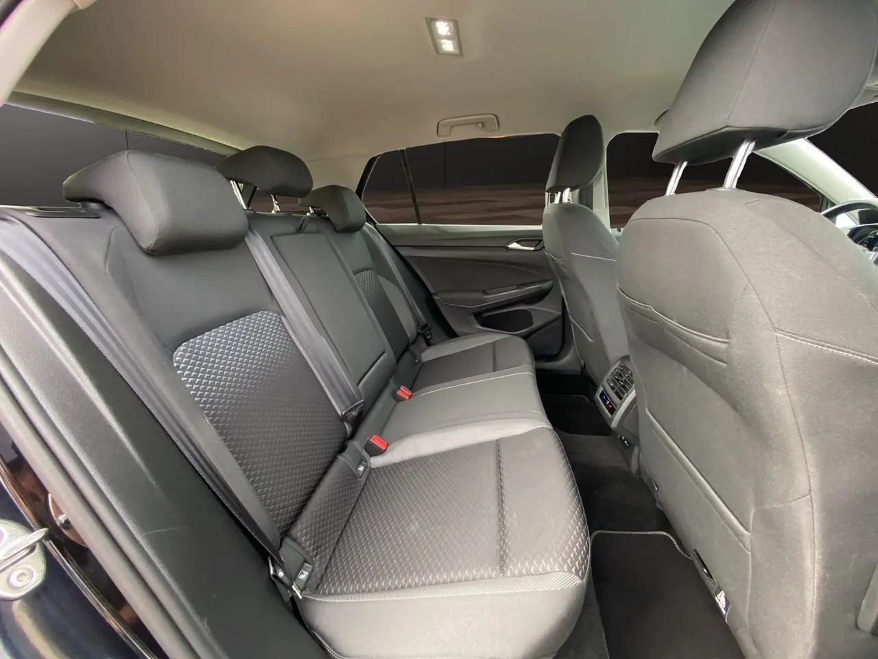 Vue intérieure côté droit des sièges arrière noirs en tissu de la Volkswagen Golf VIII 2022 avec vitres surteintées.