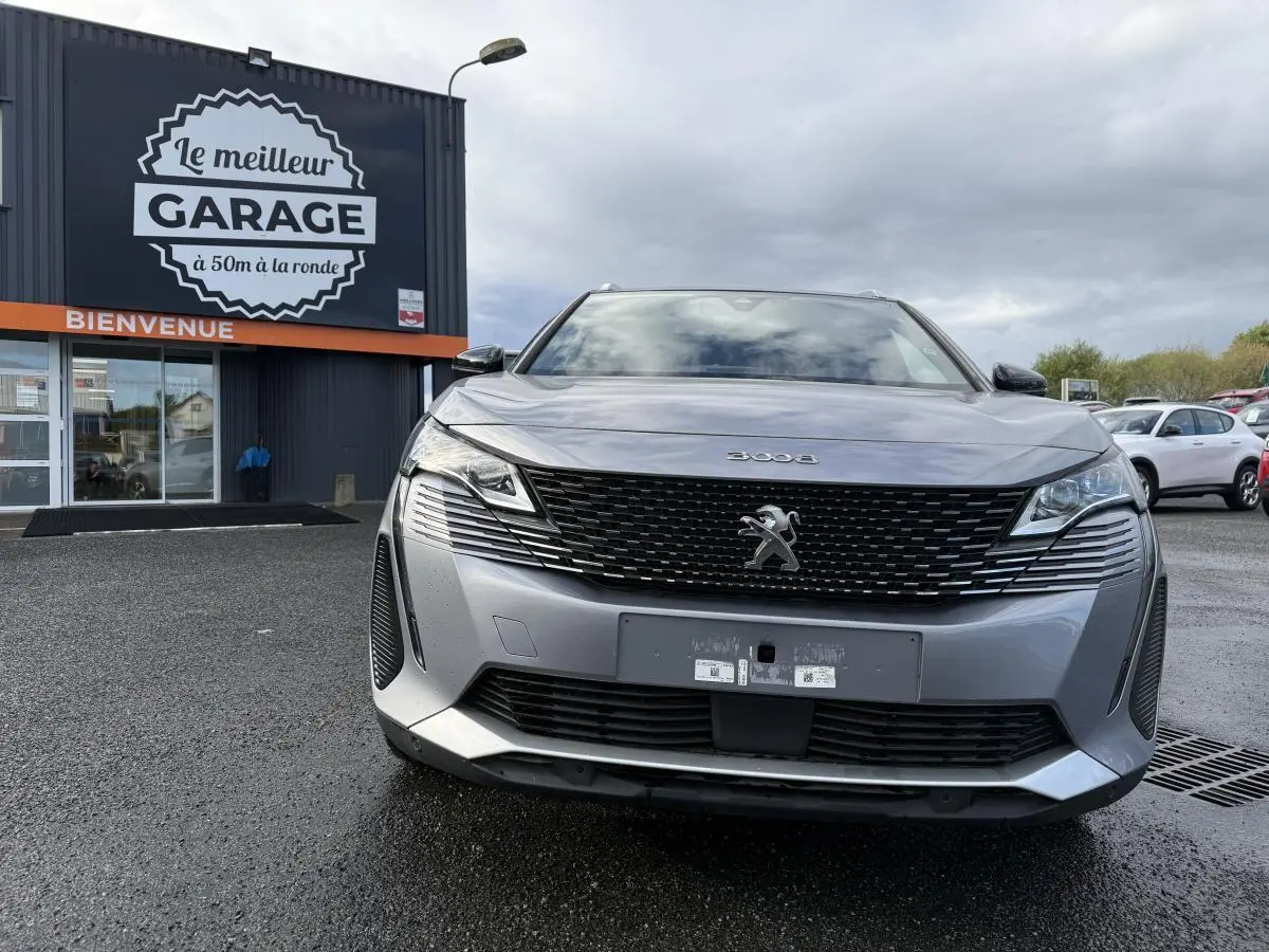 Vue frontale d'un Peugeot 3008 gris métallisé avec calandre noire et logo lion chromé visible au garage.