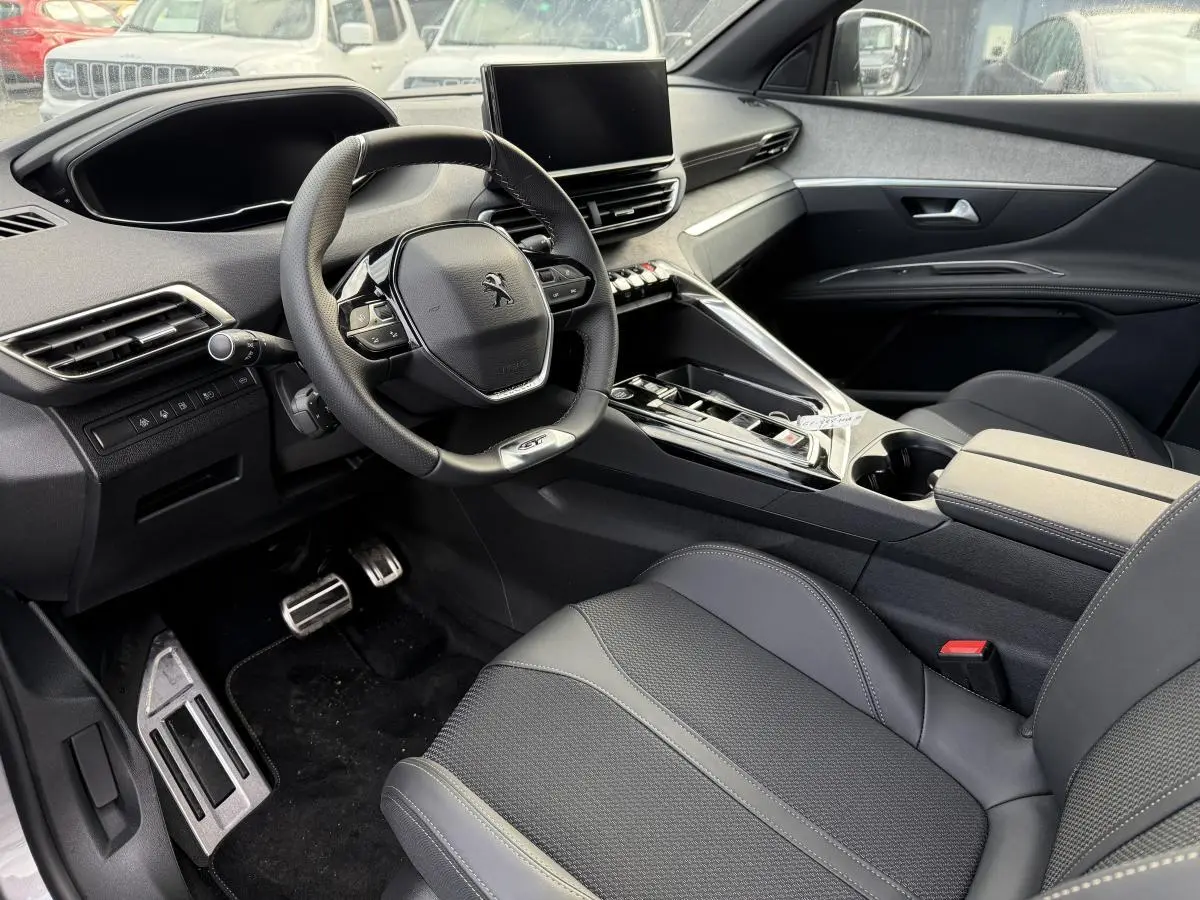 Intérieur avant droit Peugeot 3008 Hybrid 2023 avec volant cuir GT, console centrale moderne et sellerie noire Mistral.