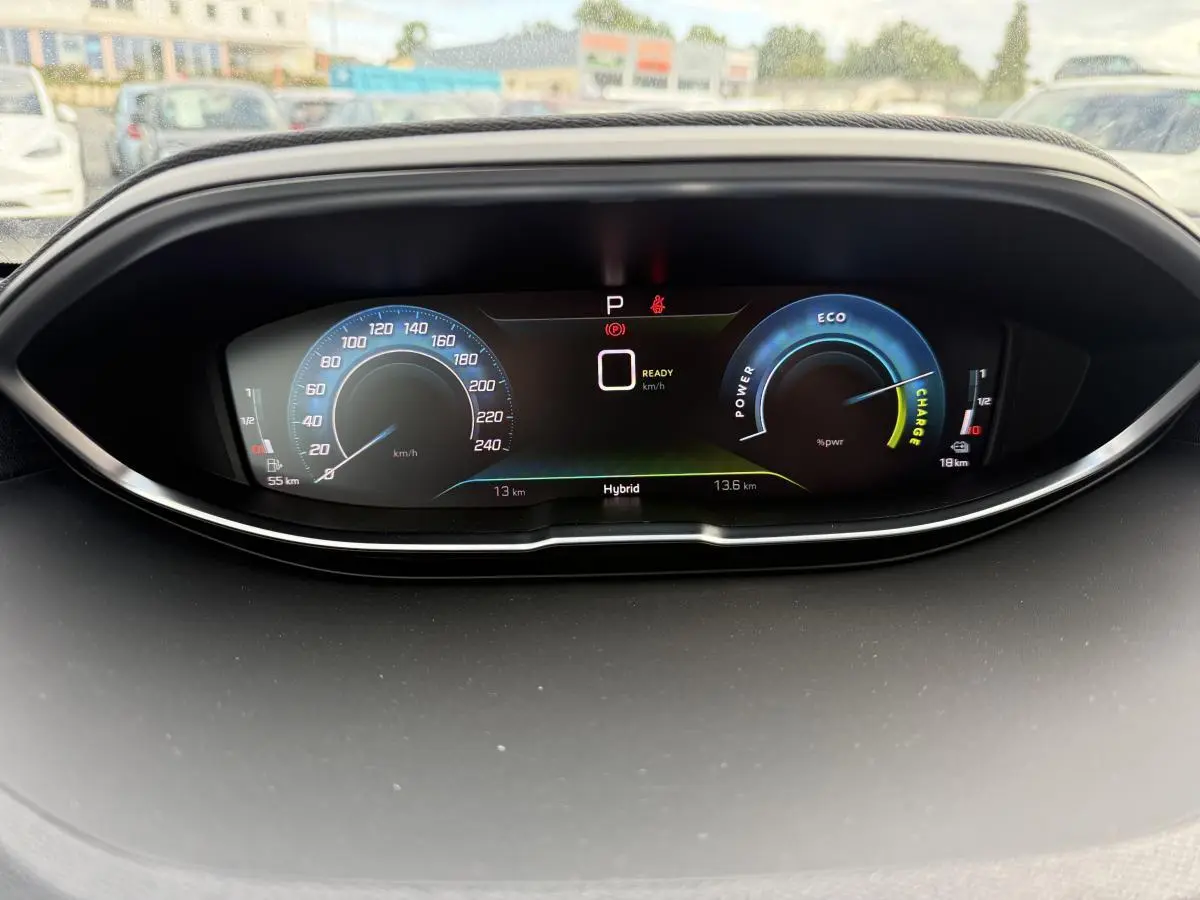 Tableau de bord numérique du Peugeot 3008 Hybrid 2023 affichant vitesse, mode hybride et jauges d'énergie en vue frontale.
