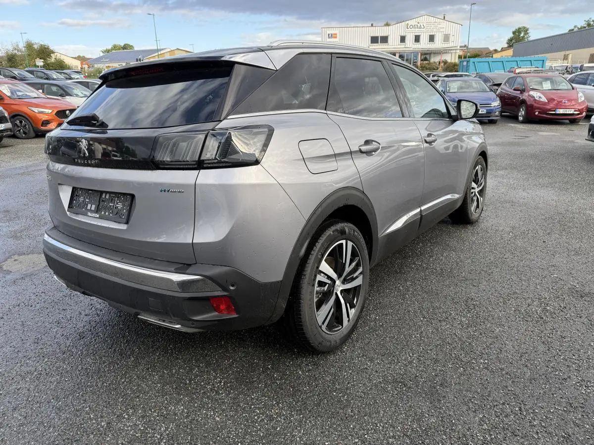 Vue 3/4 arrière droite d'un Peugeot 3008 Hybrid gris métallisé avec jantes bi-ton et vitres arrière surteintées.