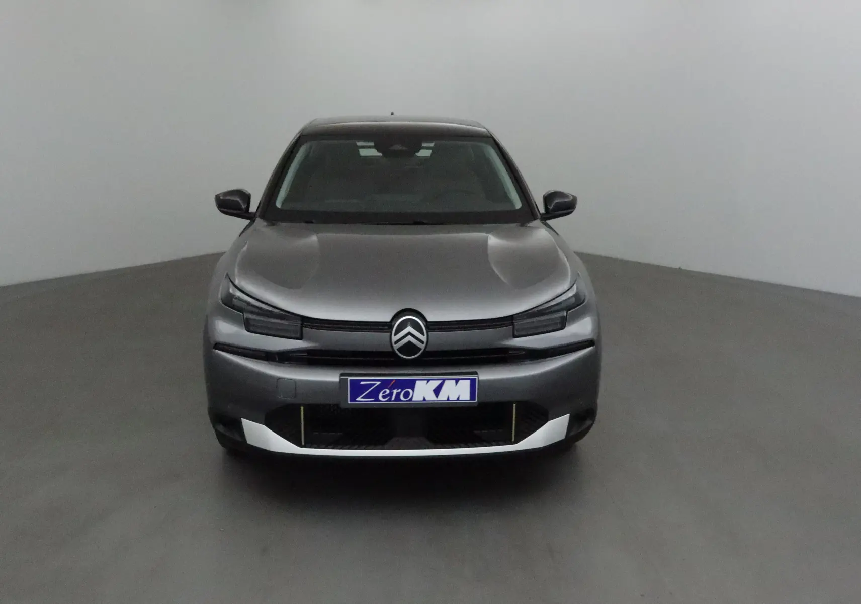 Vue frontale d'une Citroën C4 2025 gris Mercury et noir avec logo distinctif et plaque Zero KM.