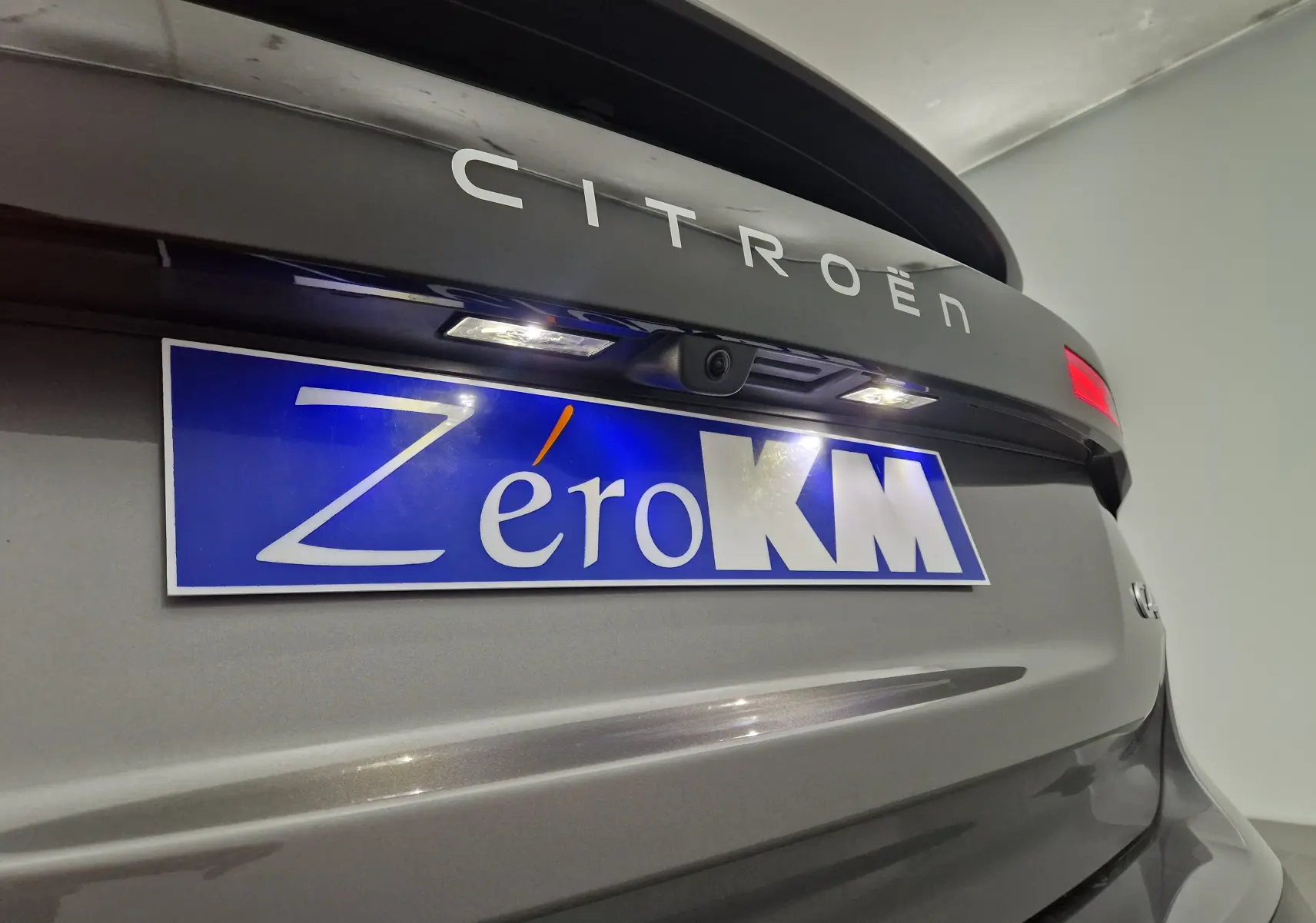 Vue rapprochée arrière du Citroën C4 gris Mercury avec plaque "Zéro KM" et caméra de recul intégrée.