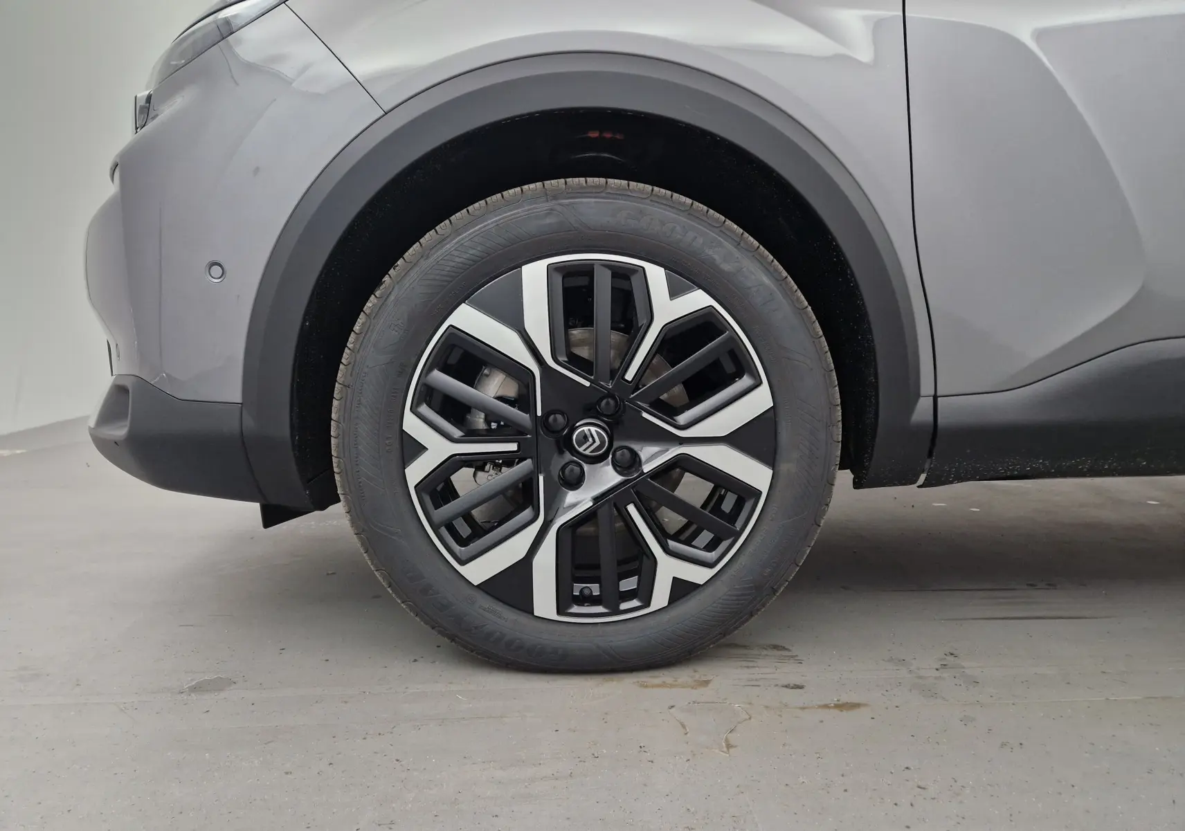 Gros plan sur la roue avant gauche de la Citroën C4 2025 gris Mercury/noir avec jante alliage noire et argentée.