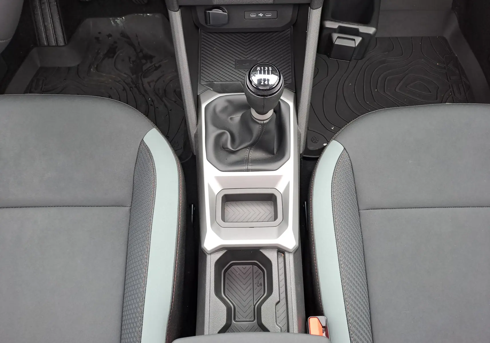 Vue plongeante sur la console centrale du Dacia Bigster noir nacré, avec levier de vitesse manuel et sièges tissu gris.