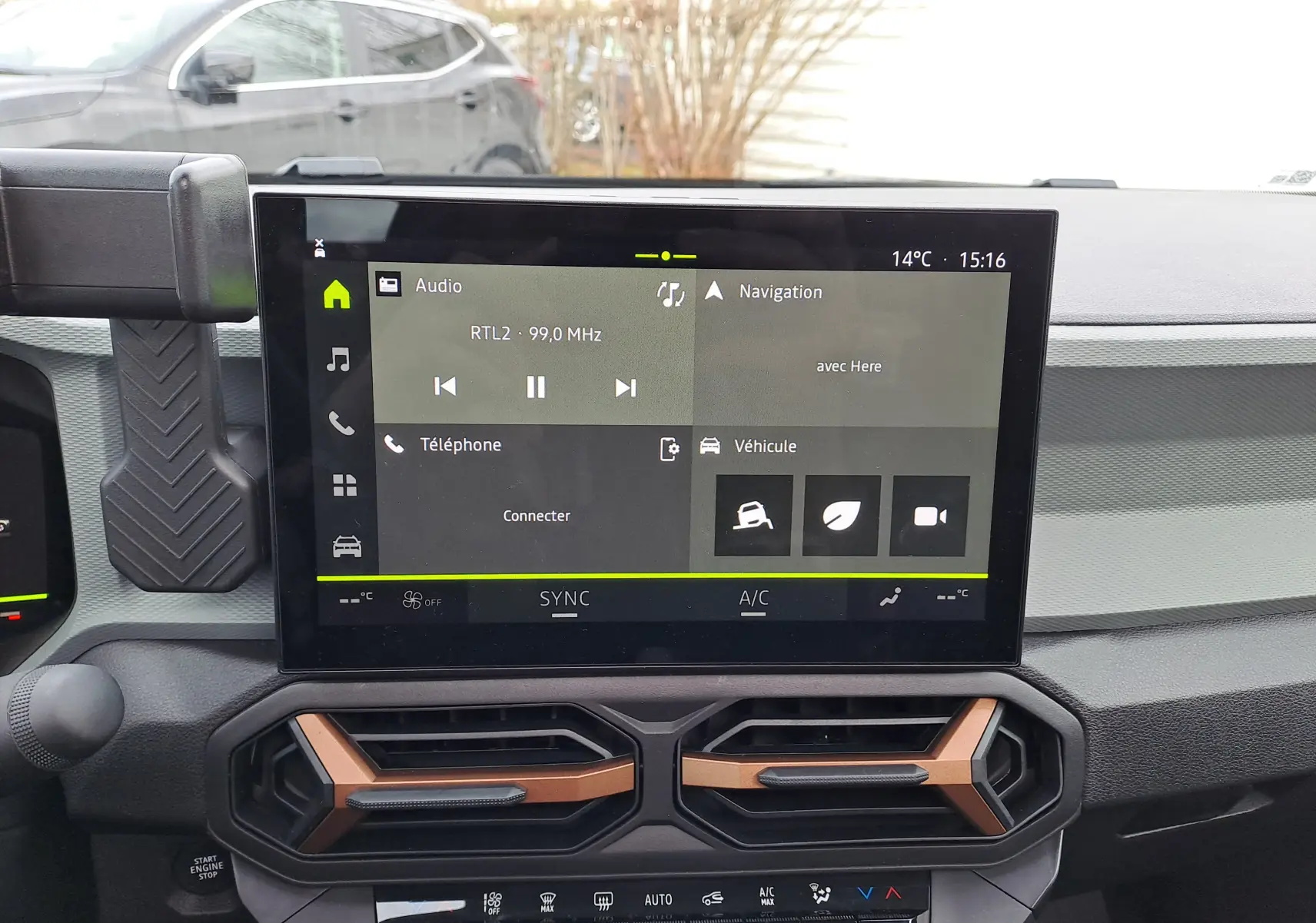 Vue intérieure centrée sur l'écran tactile et les aérateurs cuivrés du tableau de bord du Dacia Bigster noir nacré.