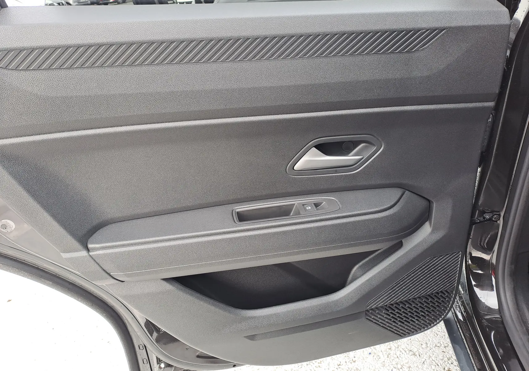 Vue rapprochée de la porte arrière droite noire nacrée du Dacia Bigster 2025, avec poignée et commande de fenêtre.