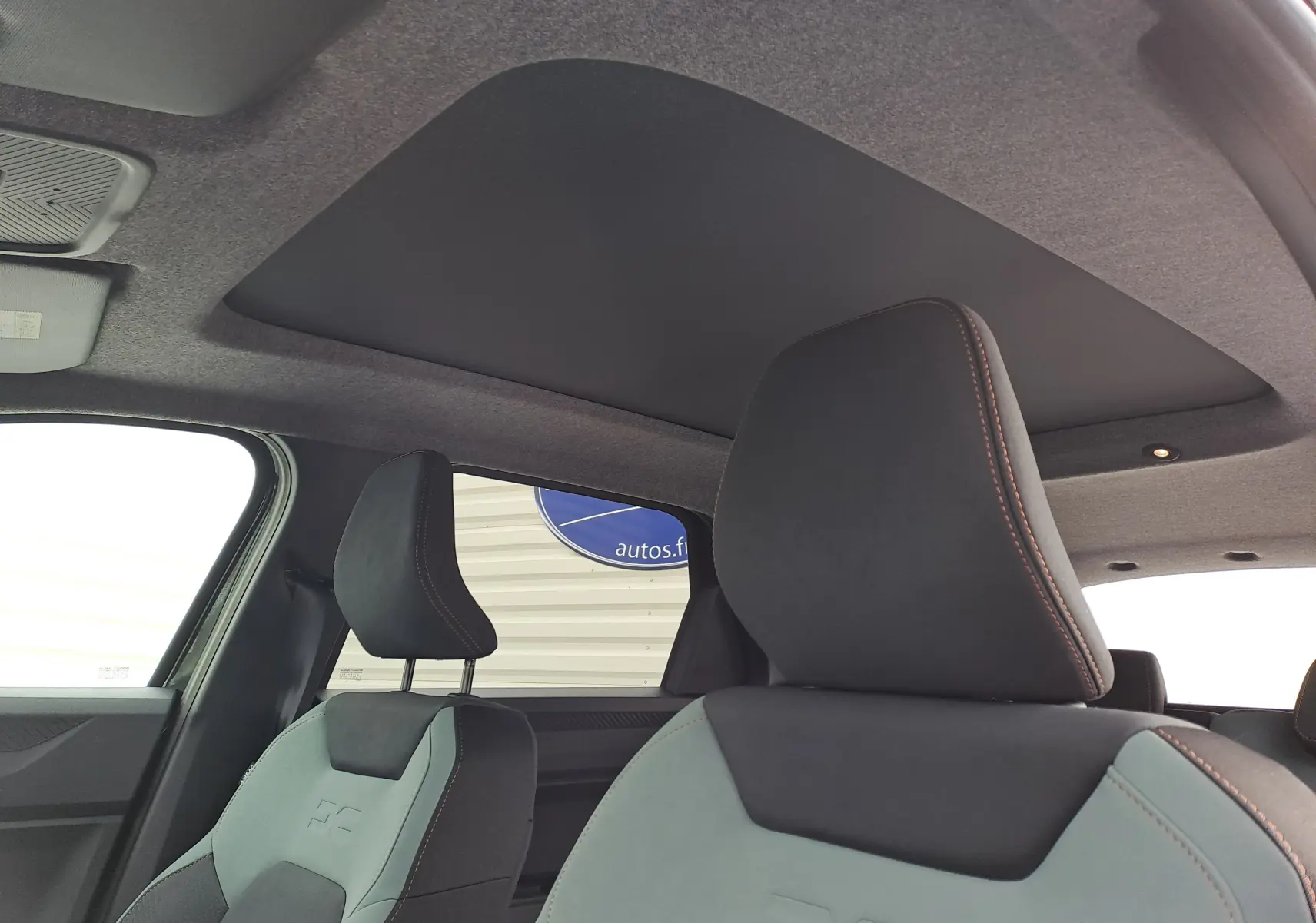 Vue intérieure sur les sièges avant gris et noir avec surpiqûres orange du Dacia Bigster 2025 noir nacré.