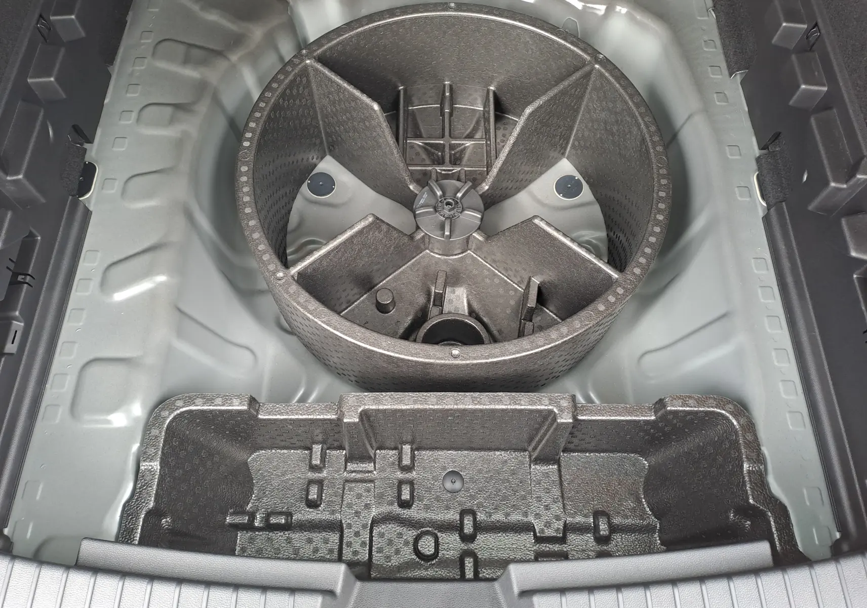 Vue plongeante sur le rangement sous le coffre du Dacia Bigster noir nacré, montrant les compartiments en mousse de protection.