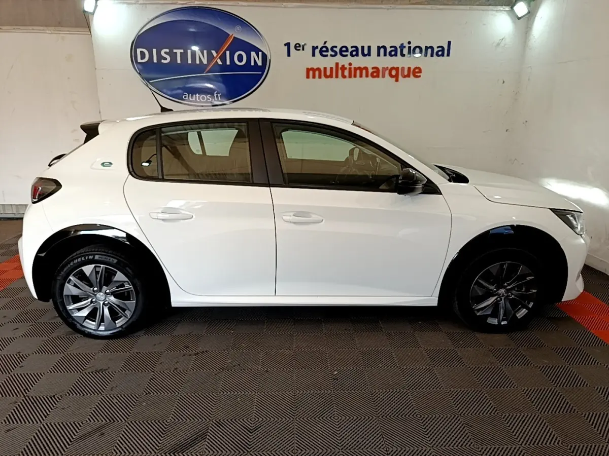 Peugeot 208 électrique blanche vue de profil côté droit, avec jantes alliage et logo "e" sur l'aile arrière.