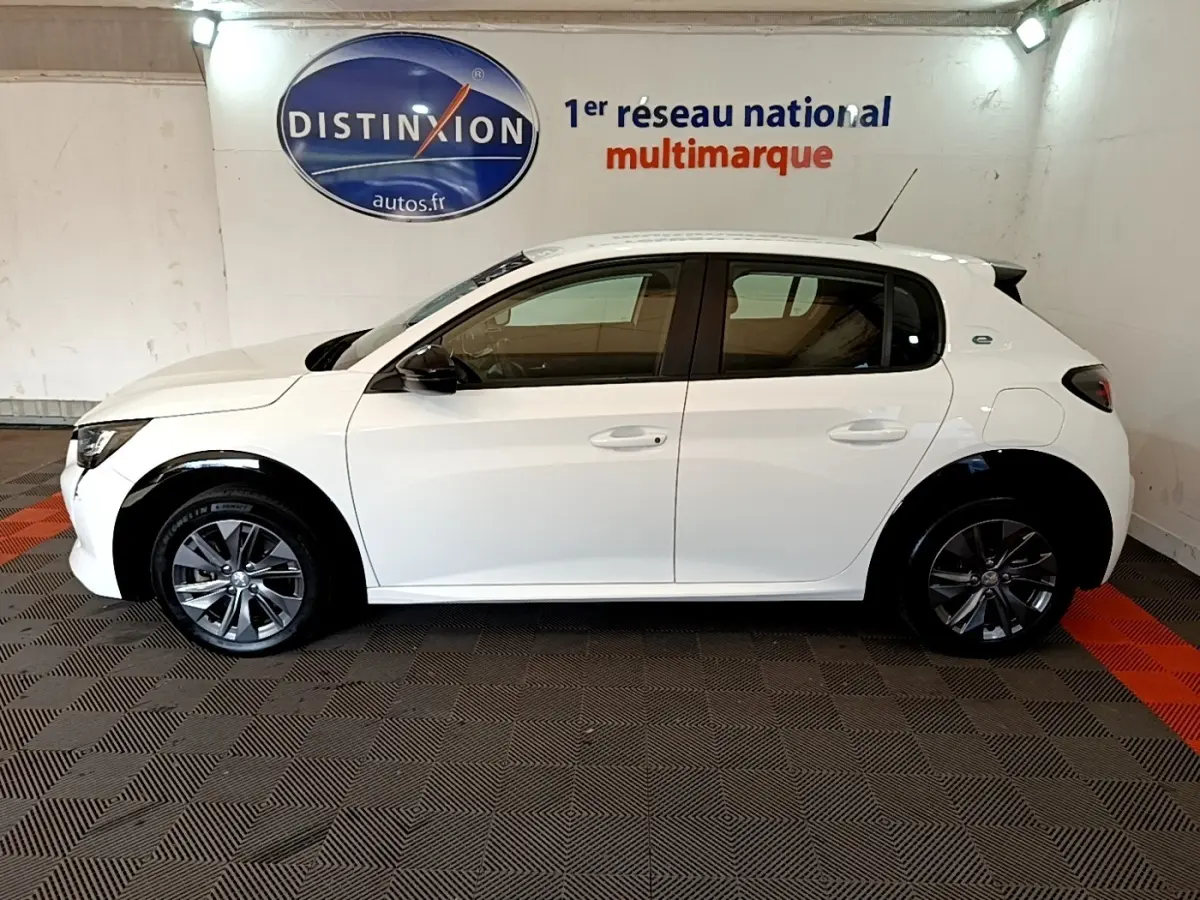Peugeot 208 électrique blanche vue de profil côté gauche, avec jantes foncées et logo "e" arrière.