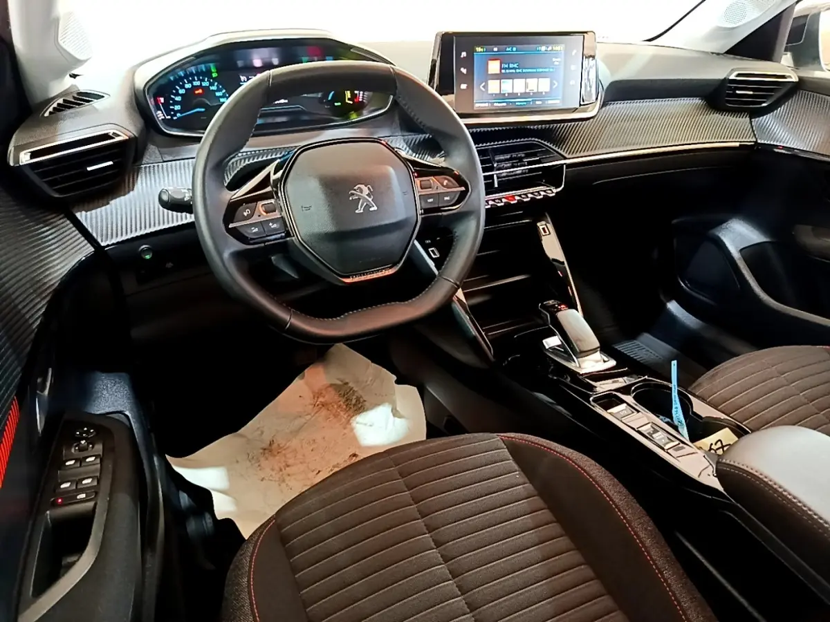Intérieur de la Peugeot 208 électrique vue côté conducteur, volant cuir, tableau de bord numérique et écran tactile central.