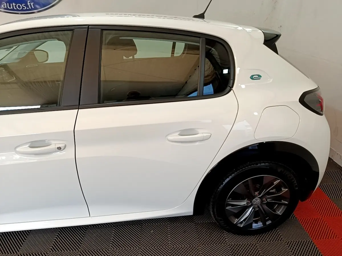 Vue latérale droite d'une Peugeot 208 électrique blanche, mettant en valeur la porte arrière et la jante noire.