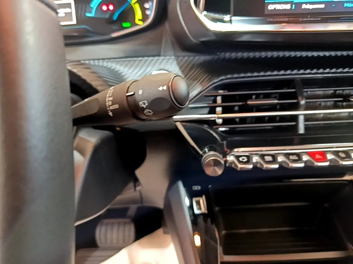 Gros plan intérieur sur la commande d’essuie-glace et la console centrale noire du tableau de bord de la Peugeot 208 électrique.