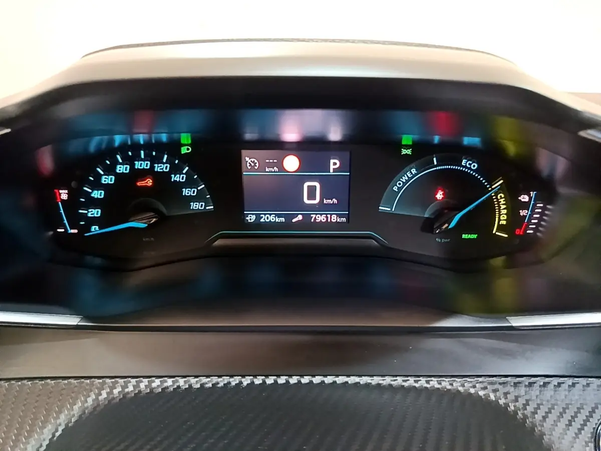 Vue rapprochée du tableau de bord numérique de la Peugeot 208 électrique, affichant la vitesse à 0 km/h et l'autonomie restante.