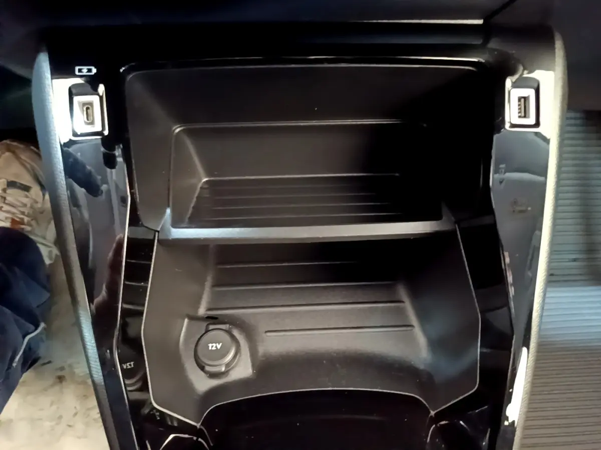 Vue rapprochée de la console centrale noire avec prises USB et prise 12V du Peugeot 208 électrique blanc.