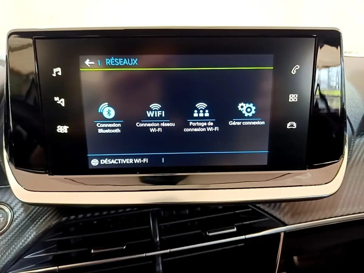 Écran tactile central affichant les options réseau dans l’habitacle du Peugeot 208 électrique blanc, vue intérieure frontale.