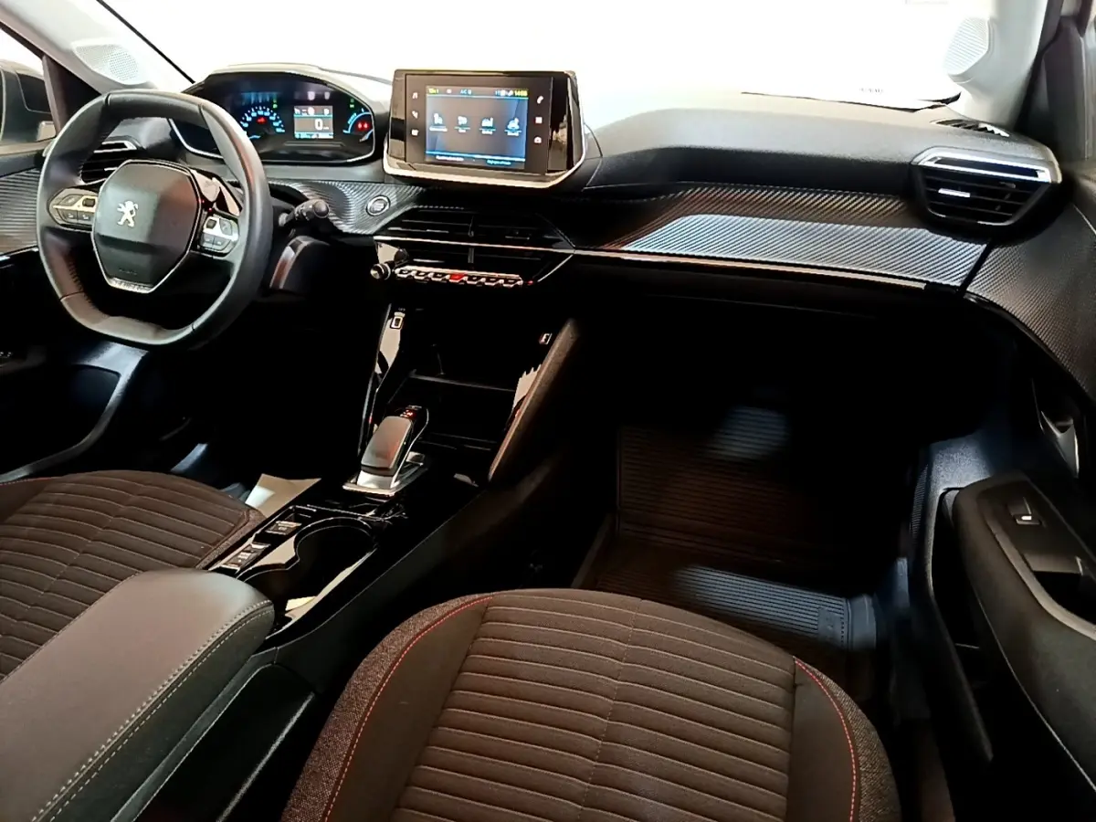 Vue intérieure avant de la Peugeot 208 électrique 2022, tableau de bord noir avec écran tactile central et volant compact cuir.