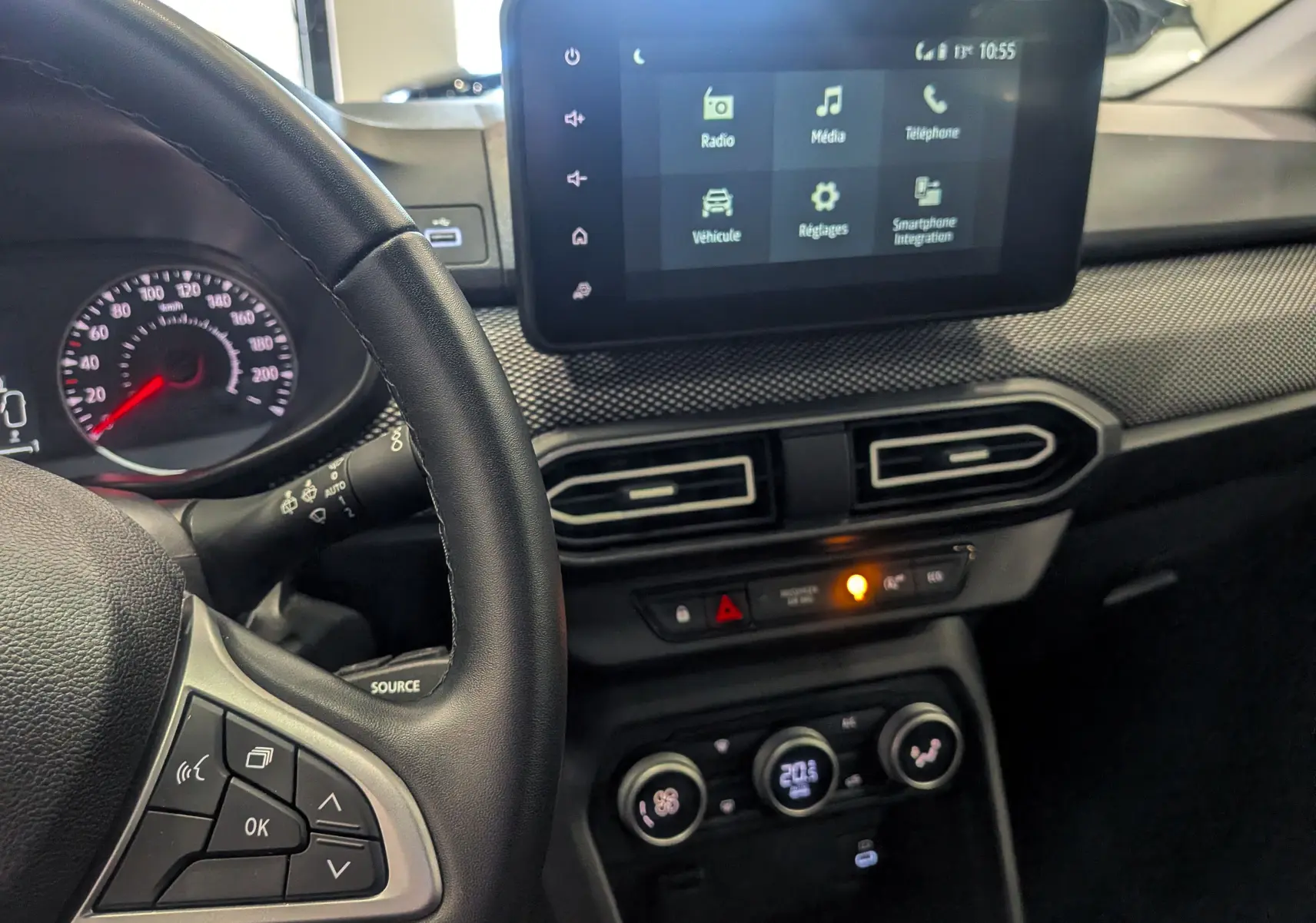 Vue intérieure du tableau de bord de la Dacia Sandero TCe 90 2025, avec écran tactile et volant à gauche en cuir noir.