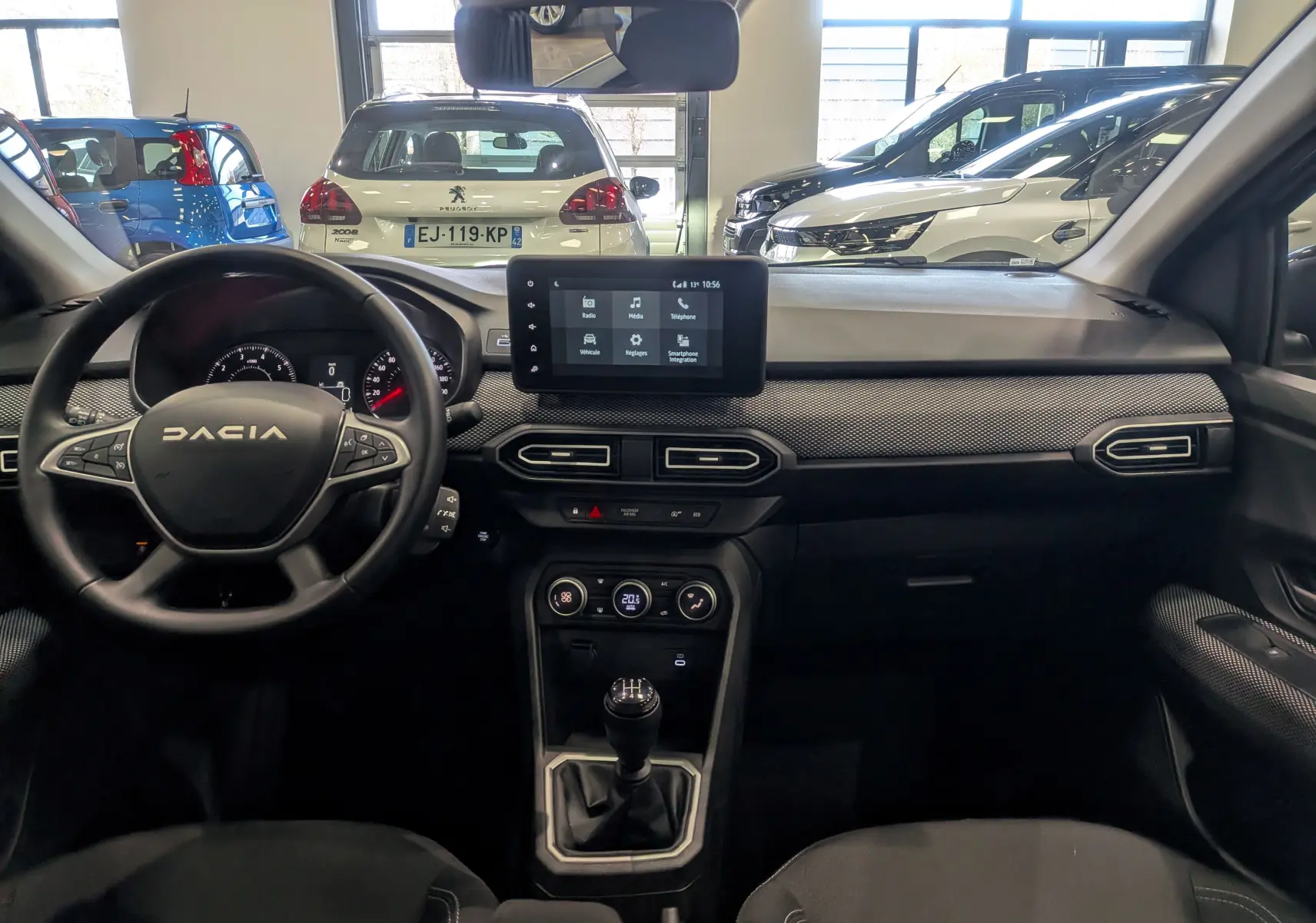 Vue intérieure avant de la Dacia Sandero TCe 90 gris schiste, avec tableau de bord moderne et boîte manuelle visible.