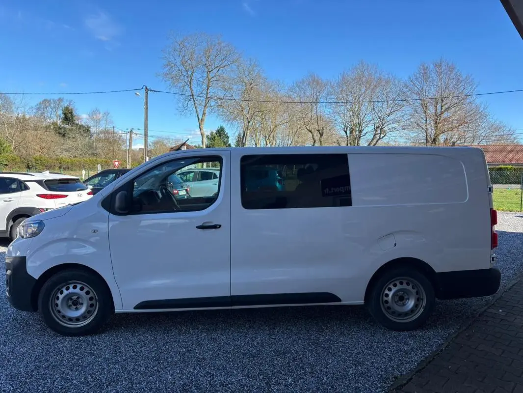 Peugeot Expert Fourgon blanc vu de profil côté gauche, avec fenêtre teintée sur la porte coulissante arrière.