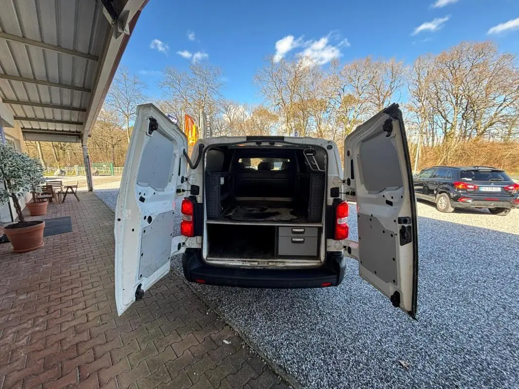 Vue arrière du Peugeot Expert Fourgon blanc 2018 avec portes ouvertes montrant l'intérieur aménagé de rangement.