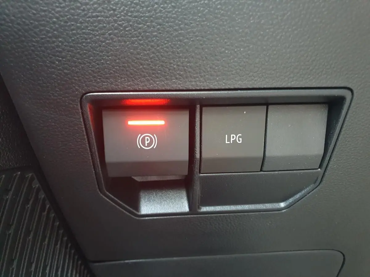Gros plan sur les boutons de commande du frein de stationnement et du mode GPL dans l'habitacle du Dacia Duster gris schiste.