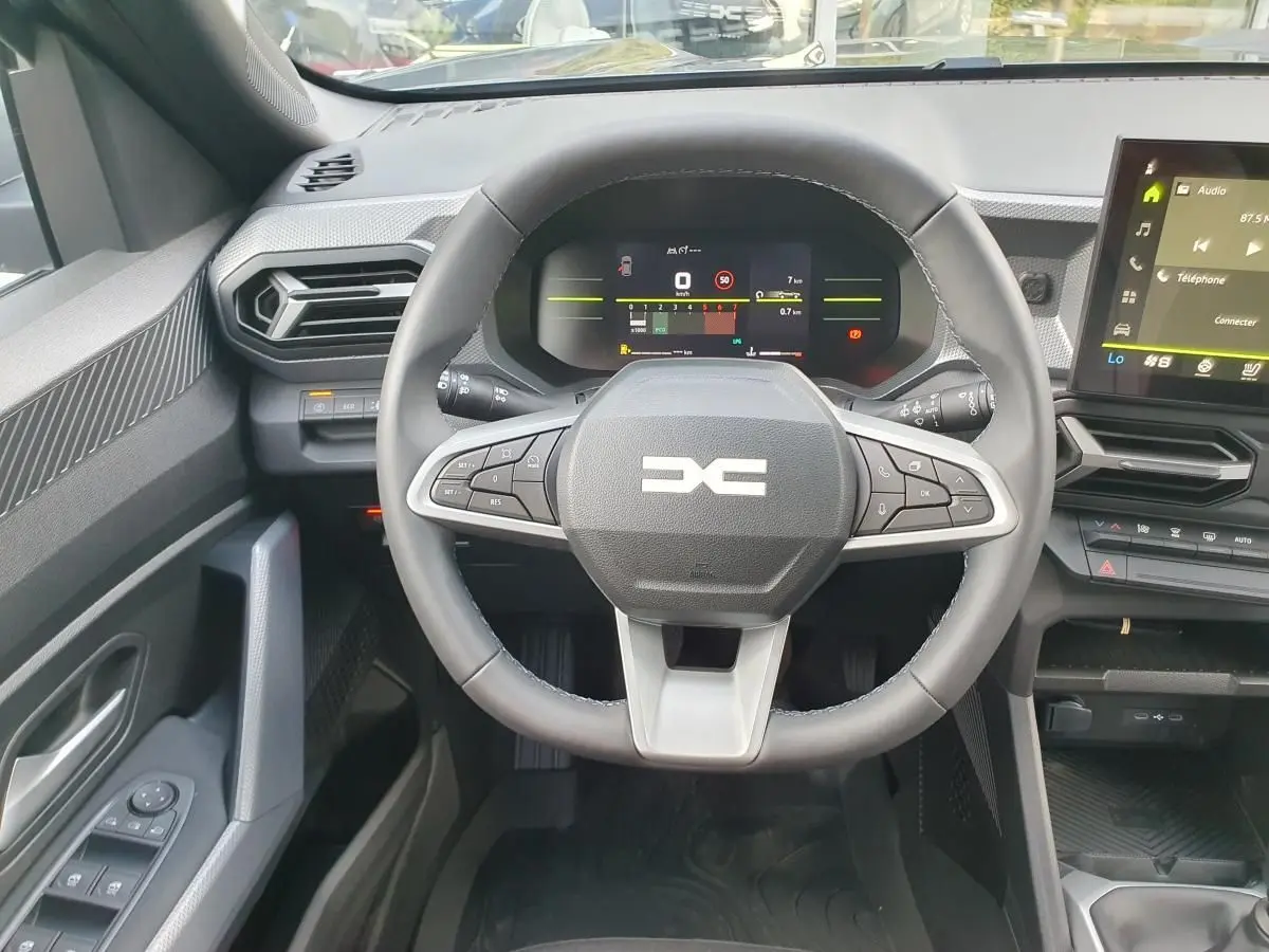 Vue intérieure centrée sur le volant multifonction du Dacia Duster 2026 avec tableau de bord numérique et écran tactile.