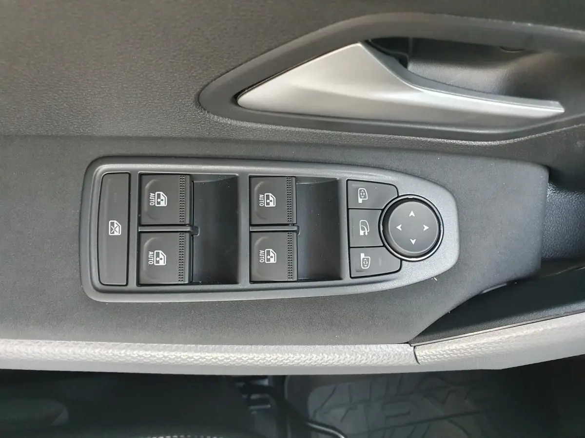 Gros plan sur les commandes de lève-vitres et rétroviseurs côté conducteur du Dacia Duster gris schiste 2026.