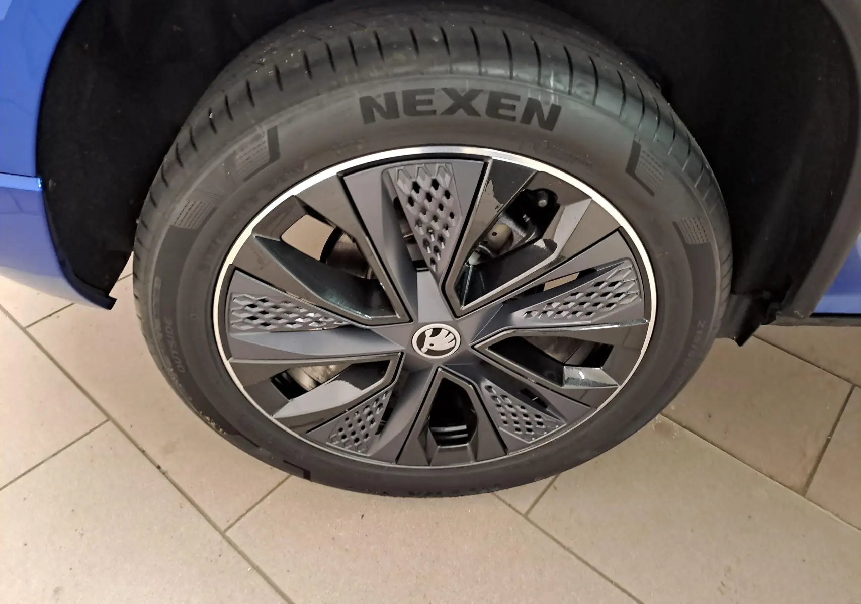 Gros plan sur la roue avant droite d’un Skoda Karoq Bleu RS avec jante alliage noire au design moderne.