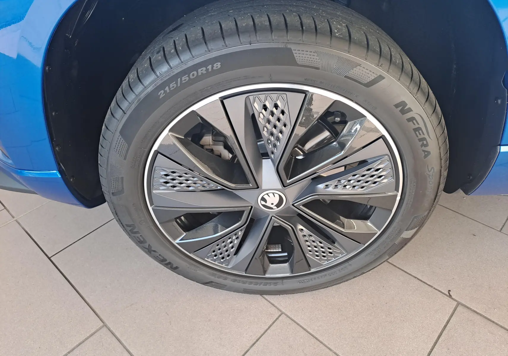 Gros plan sur la roue avant droite du SKODA KAROQ Bleu RS avec jante alliage noire et grise au design moderne.