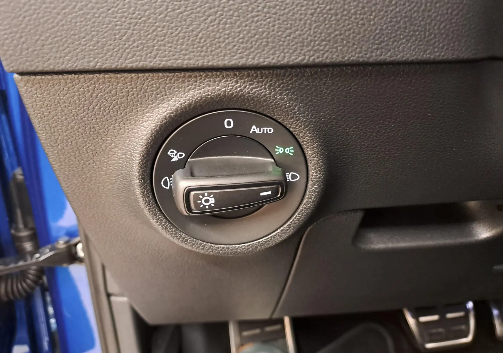 Gros plan sur le bouton de commande des phares dans l'habitacle d'une SKODA KAROQ Bleu RS, côté conducteur.
