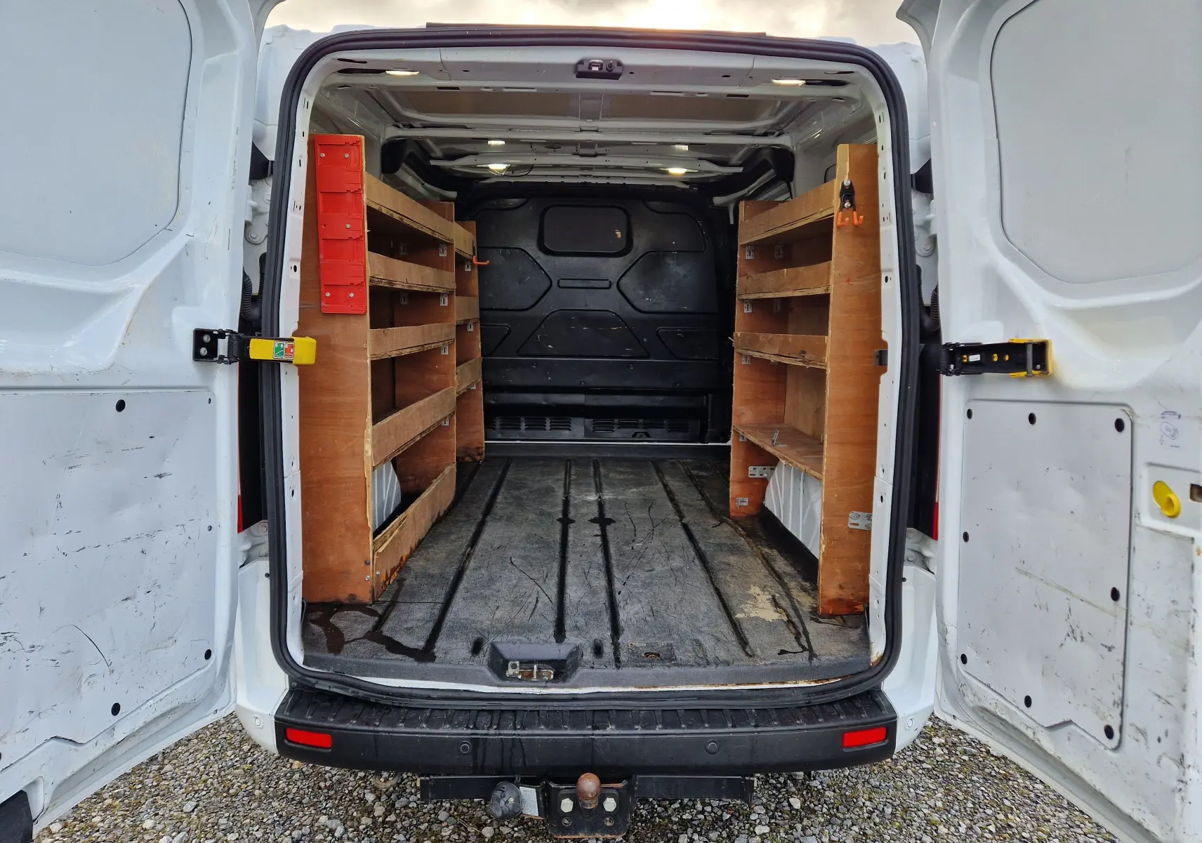 Vue intérieure arrière droite du Ford Transit Custom blanc 2021, montrant des étagères en bois fixées dans le fourgon.