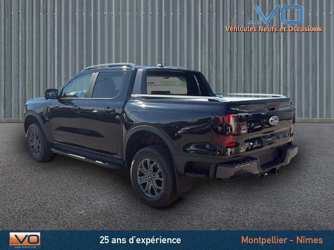 Vue 3/4 arrière droite du Ford Ranger noir 2025 avec barres de toit, marchepieds et jantes alliage 18 pouces.