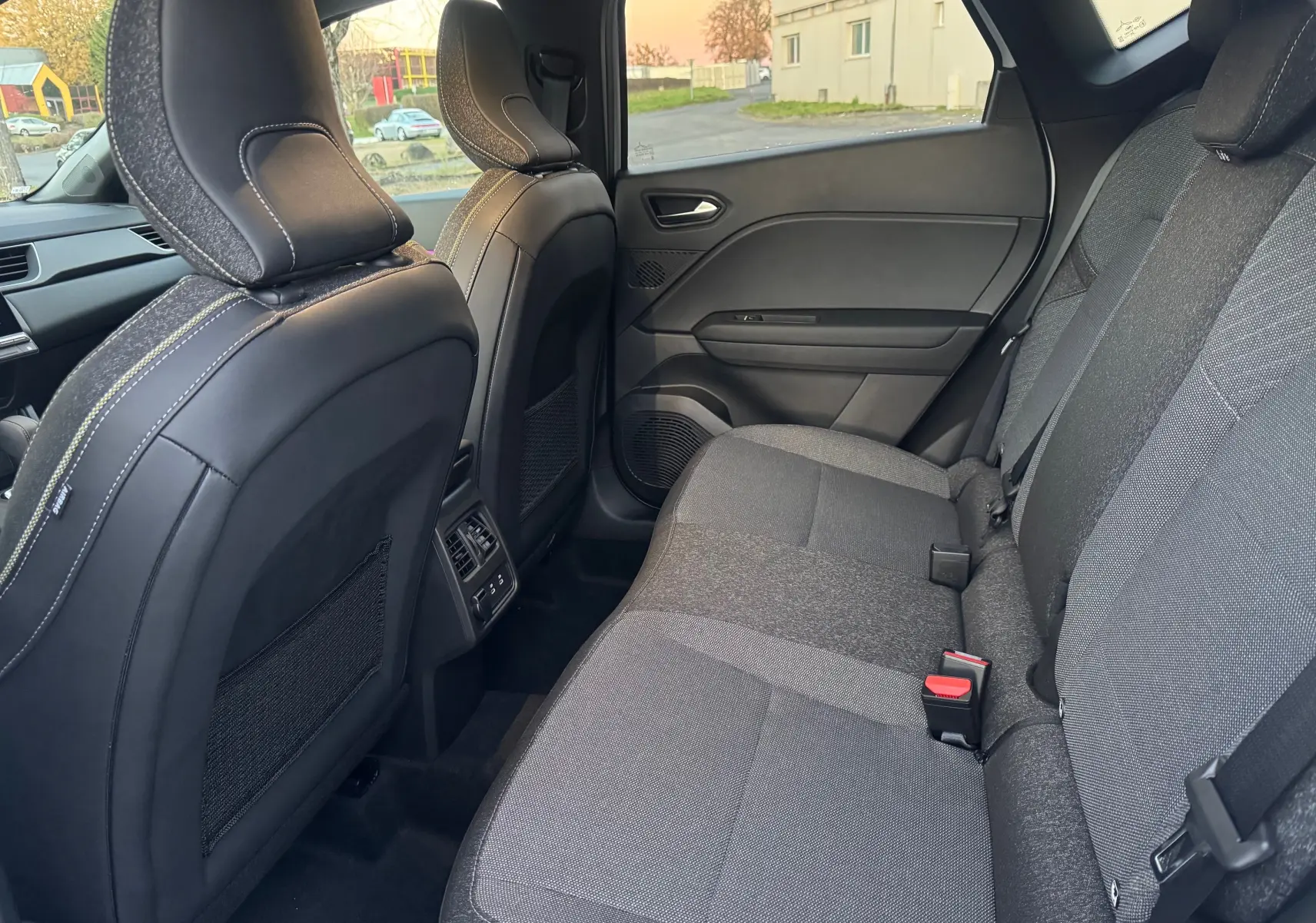 Vue intérieure côté droit des sièges arrière gris foncé du Renault Captur E-Tech Hybrid 2025 avec appuie-têtes et aérateurs centraux.