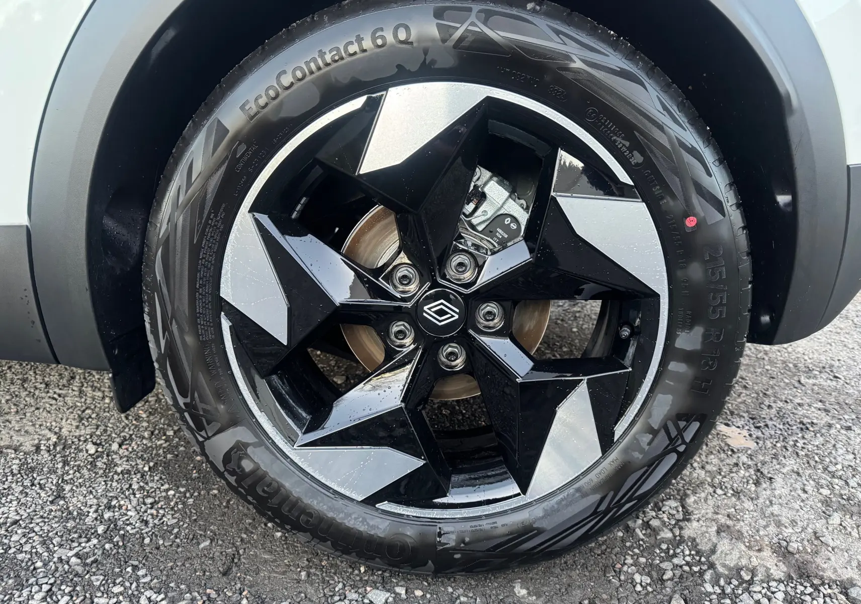 Gros plan sur la roue avant droite du Renault Captur blanc nacré, jante noire et argent au design géométrique.