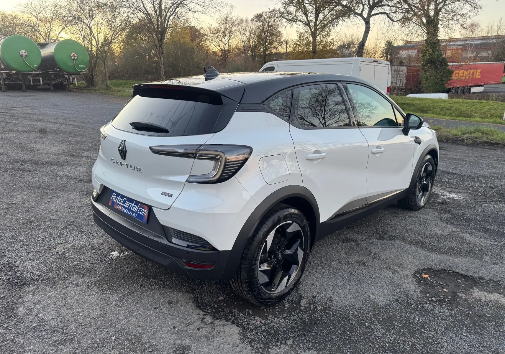 Vue 3/4 arrière droite d'un Renault Captur blanc nacré avec toit noir et jantes noires au design moderne.
