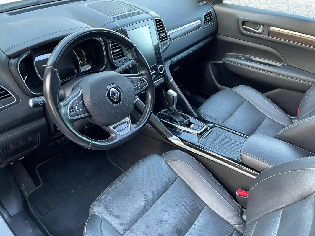 Vue intérieure côté conducteur du Renault Koleos 2019, tableau de bord noir avec écran tactile et accoudoir central.