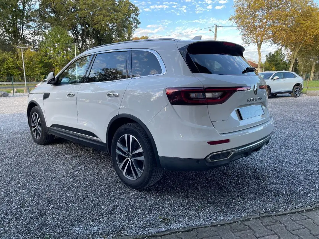 Renault Koleos blanc vu en 3/4 arrière droit, avec feux arrière allongés et jantes alliage distinctives.