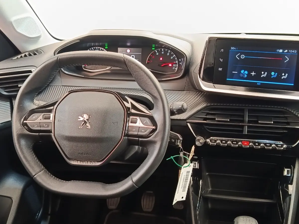 Vue intérieure centrée sur le volant cuir multifonctions et l’écran tactile du tableau de bord de la Peugeot 208 noire.
