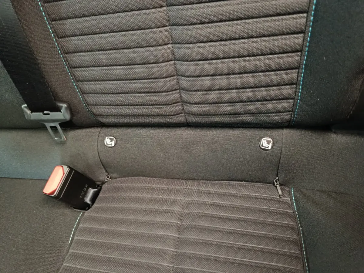 Gros plan sur la banquette arrière noire de la Peugeot 208 PureTech 100 S&S Style avec surpiqûres bleues et attaches Isofix visibles.